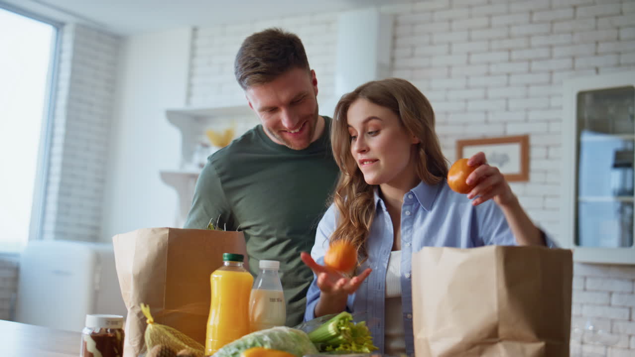 Closeup pair sorting food together in kitchen. Family taking purchased products