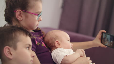 los niños se toman selfies con el teléfono móvil en casa. los hermanos con el bebé se toman selfies