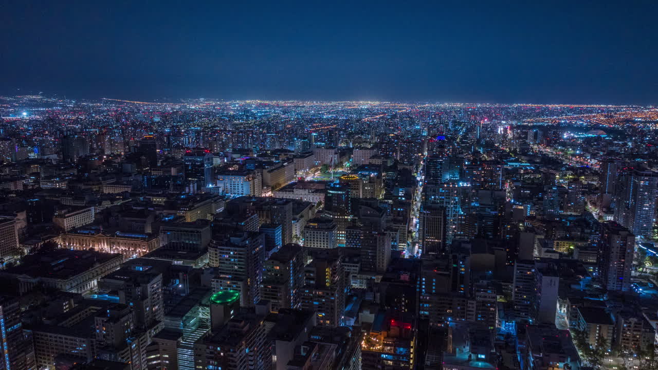 Aerial hyperlapse zooming in with elevation over Santiago de Chile at night, transitioning to a wide zoom out revealing the illuminated cityscape