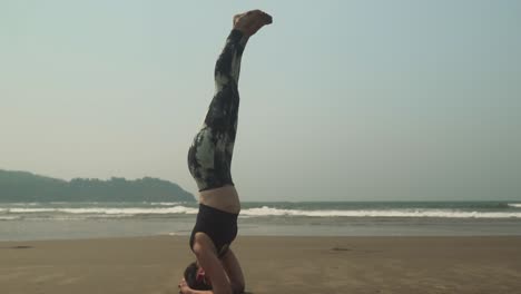 Frauen-Machen-Yoga-Im-Kopfstand,-Während-Sie-Am-Strand-üben