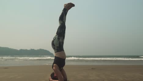 mujeres haciendo posición de yoga de cabeza mientras practican a lo largo de la playa