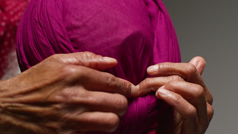 un hombre envolviendo un turbante rosa alrededor de su cabeza