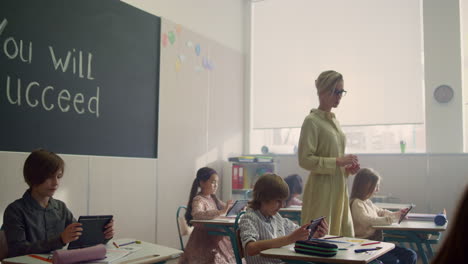 teacher looking students at lesson. children learning with digital tablets