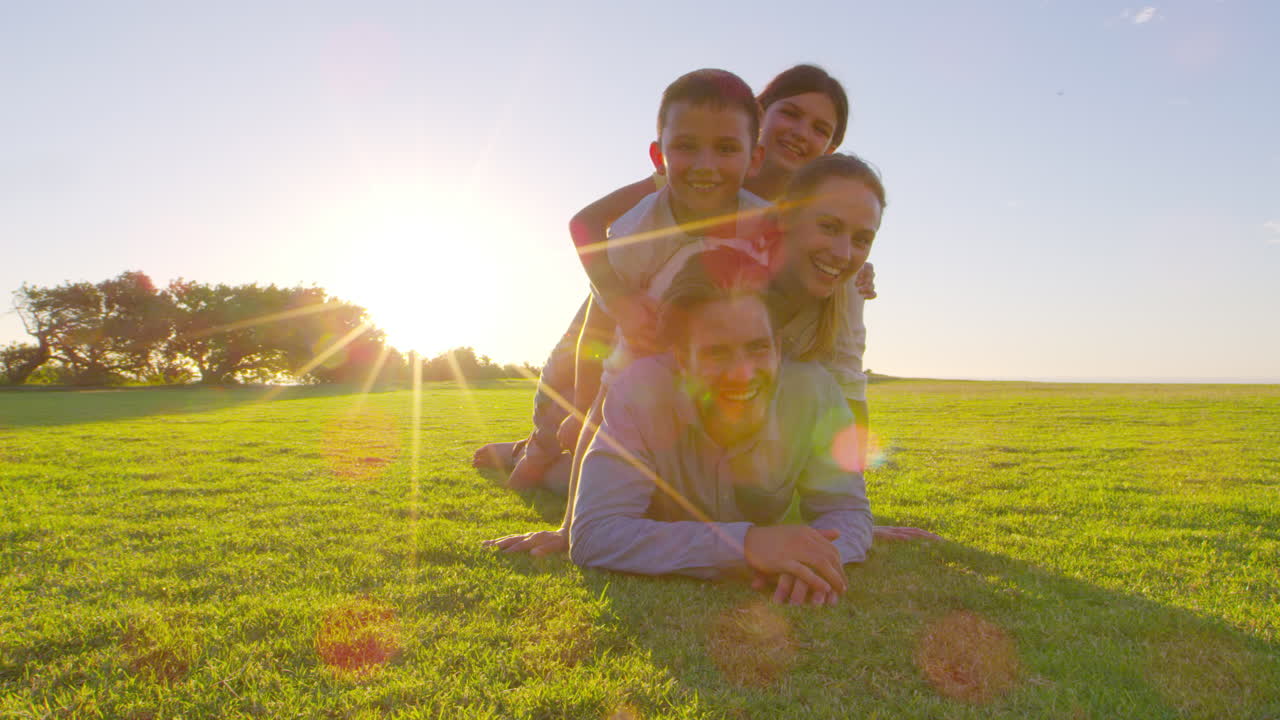 Família branca feliz deitada em pilha na grama ao ar livre