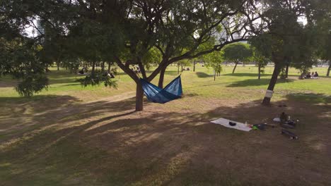 Alejar-La-Foto-De-Una-Mujer-Morena-Acostada-En-Una-Hamaca-En-El-Parque-Durante-El-Día-Soleado