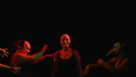 women dance in masks in colorful lighting, snap zoom closeup