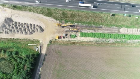 very high aerial drone shot of a construction site next to a highway