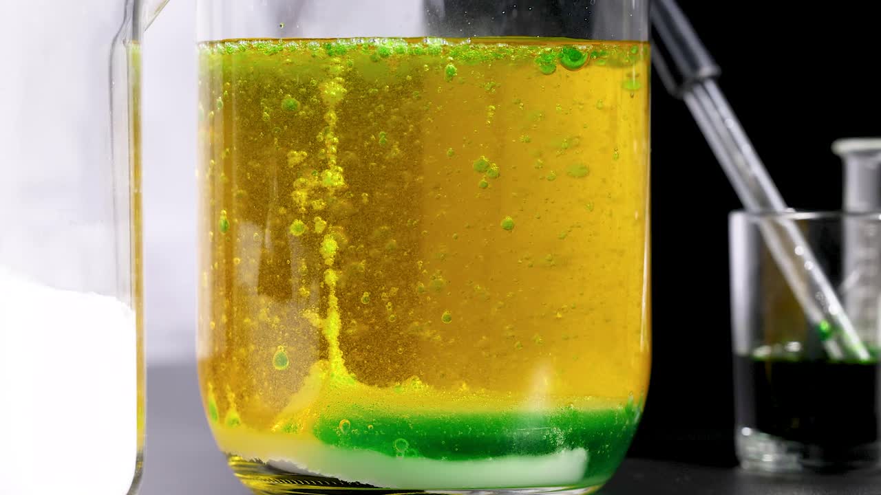 실험실 컵에서 활발한 화학 반응이 일어나며, 역동적인 색상 변화와 액체 움직임을 보여줍니다.