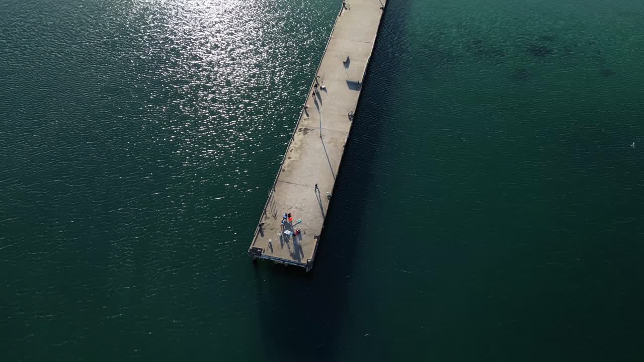 tomada aérea de un turista en el muelle disfrutando de la vista del océano pacífico en australia - estableciendo el vuelo del avión no tripulado