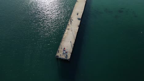 Toma-Aérea-Inclinada-Hacia-Abajo-De-Un-Turista-En-El-Embarcadero-Disfrutando-De-La-Vista-Del-Océano-Pacífico-En-Australia---Estableciendo-Un-Vuelo-De-Drones