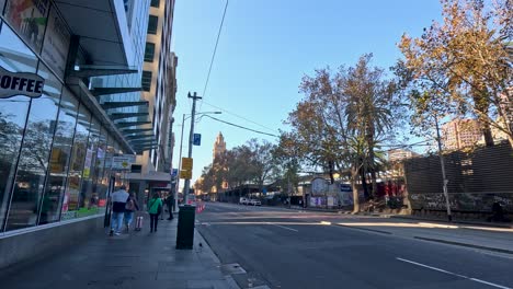 pedestrians walk past shops and streetlights