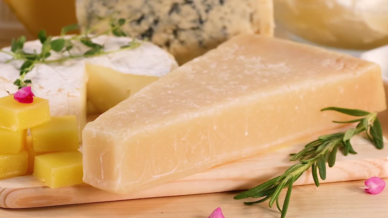 A selection of cheeses with herbs and butter slices on a wooden board.