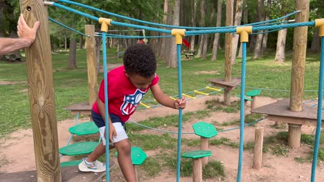 niño negro de 4 años jugando en un patio de recreo en un idílico paisaje natural