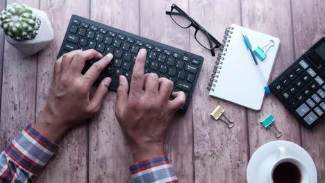 person typing on a keyboard at a wooden desk