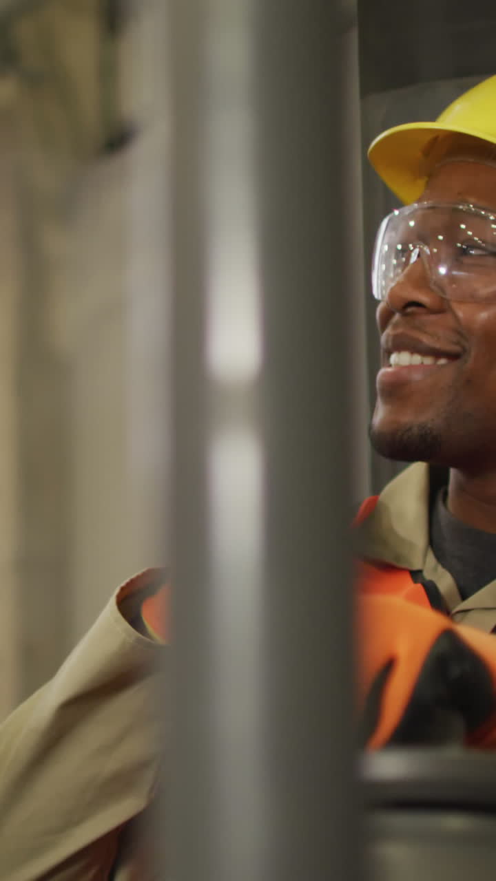 African american male worker wearing safety suit with helmet talking in warehouse