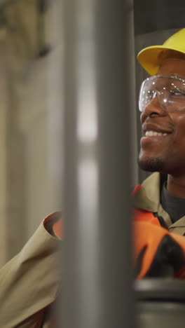 african american male worker wearing safety suit with helmet talking in warehouse