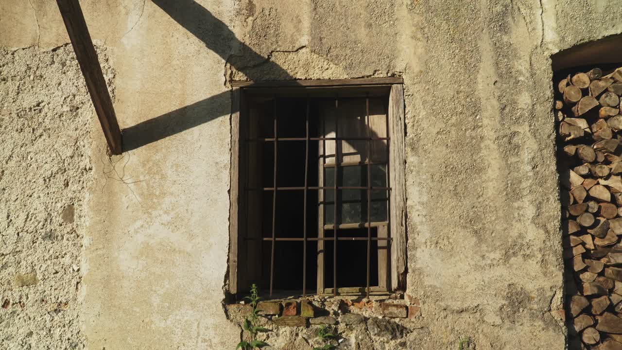 una ventana rústica con barras de metal en un viejo edificio desgastado en la luz del sol suave