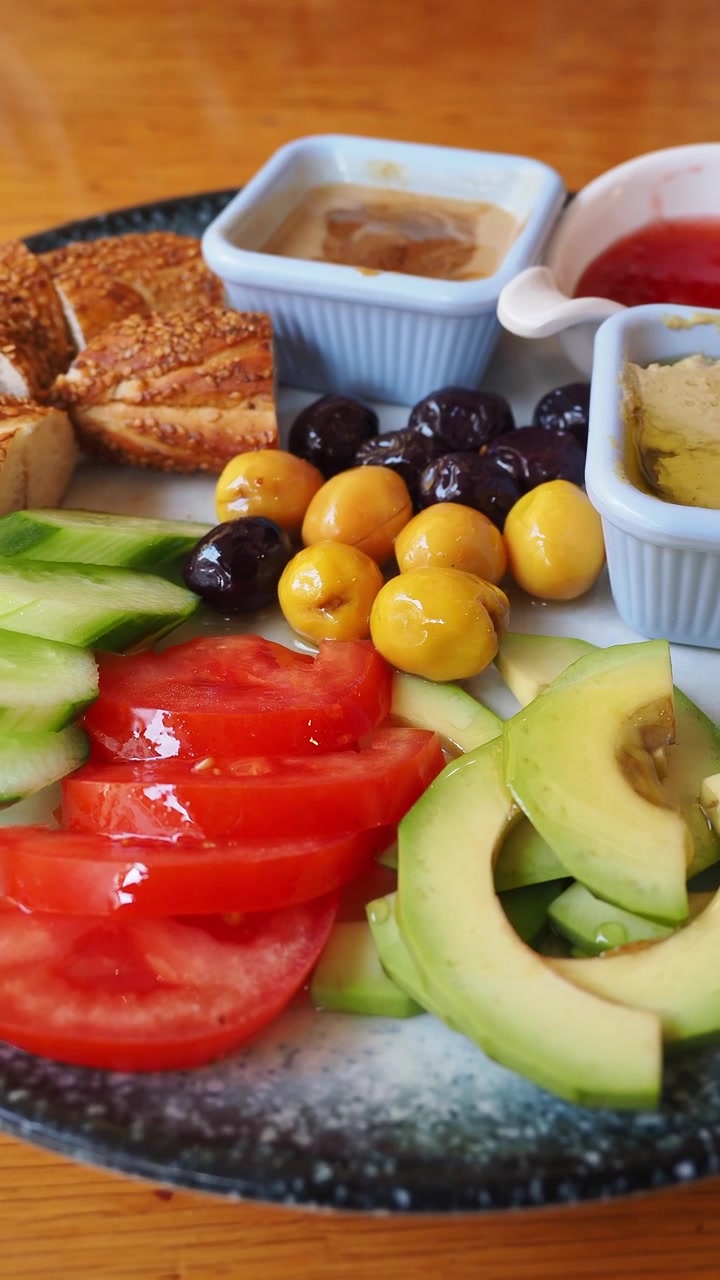 Gezond ontbijtbord met avocado, tomaten, olijven, hummus en simit