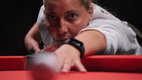 blonde woman hits cue ball into corner pocket close up red billiards pool table