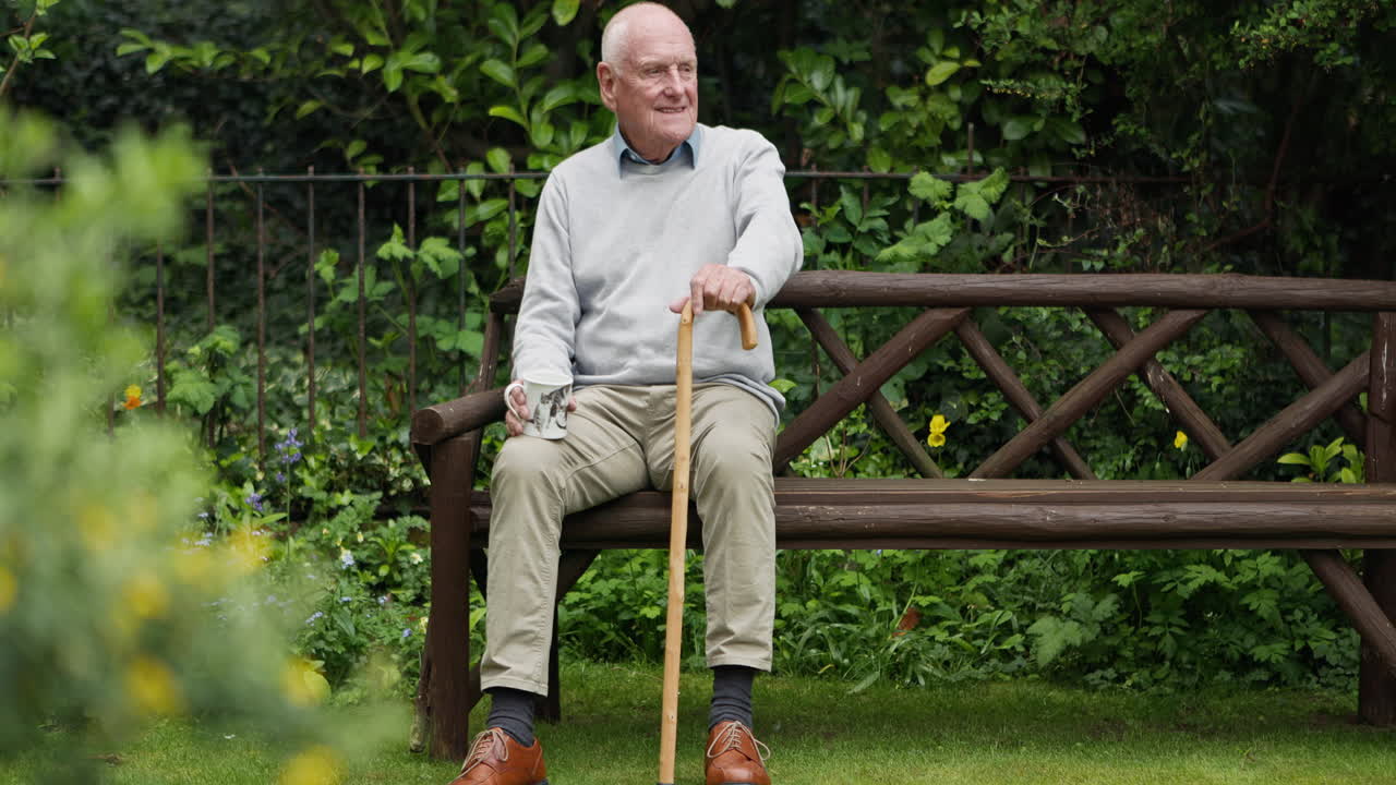 Elderly man relaxing on a park bench in his garden