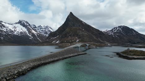Flying-over-Lofoten-Reine-mountain-peaks-overlooking-picturesque-wintry-blue-ocean