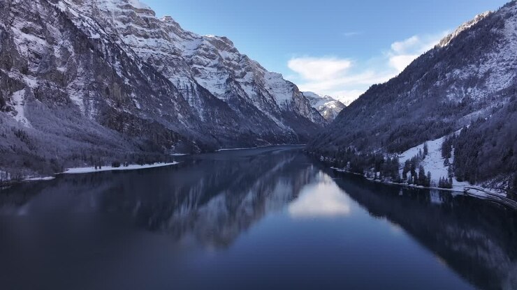 Snowy mountain landscape reflecting on Klöntalersee, serene winter scenery, Glarus