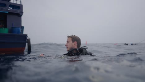 scuba diver at the ocean surface next to a boat