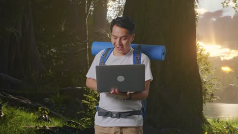 hombre con una computadora portátil caminando en el bosque al amanecer