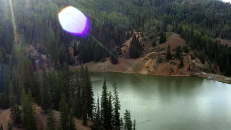 Beautiful-rotating-aerial-drone-shot-of-a-stunning-nature-landscape-of-the-Anderson-Meadow-Reservoir-lake-up-Beaver-Canyon-in-Utah-with-large-pine-tree-and-aspen-tree-forest-on-a-warm-sunny-summer-day