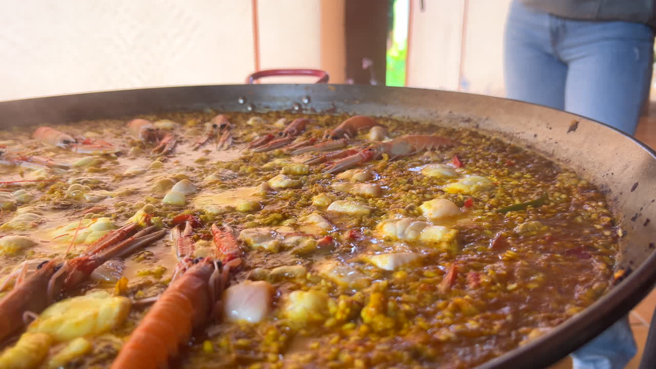 Preparing a traditional Spanish seafood Paella dish with shrimps, St Jacques scallops and Cigala Norway lobsters Nephrops norvegicus, cooked rice with seafood, Marbella Spain, 4K shot