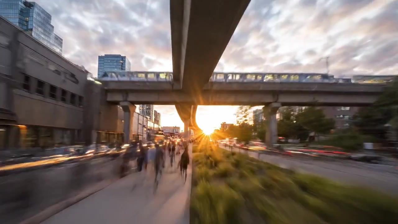 Scena urbana al tramonto con grattacieli e architettura moderna, che mostra un paesaggio cittadino sotto un cielo vibrante e strade animate piene di persone e movimento.