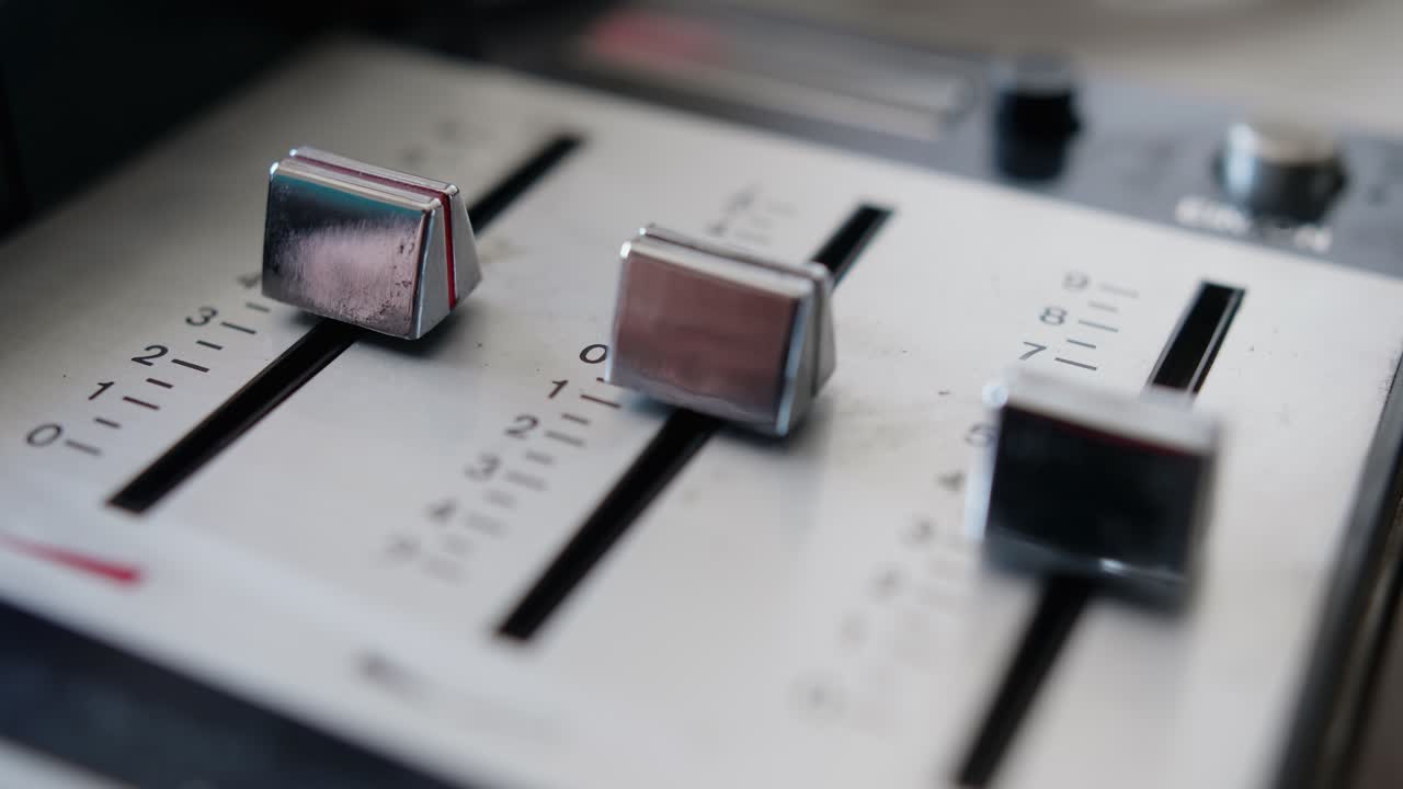 Close-up of Hand Adjusting Faders on an Audio Mixer