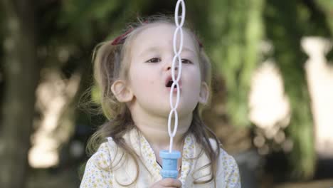 Niña-Adorable-Y-Alegre-Divirtiéndose-Con-Las-Burbujas-En-El-Parque