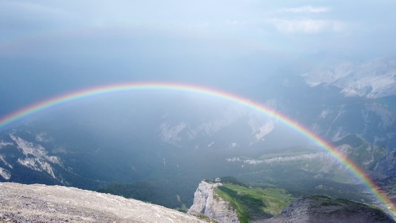 panorámica lenta de izquierda a derecha sobre un campo de grava alpino en los alpes alemanes que muestra un arco iris doble justo después de una tormenta