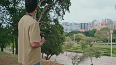 happy tourist looking cityscape holding camera back view. man taking picture