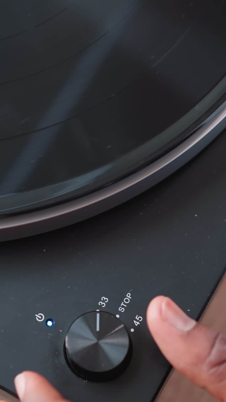 Hand of man activates switch on turntable. African American music lover entertains visitors immersed in favorite tunes through turntable. Music background