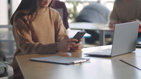 Mujer-Enviando-Mensajes-Por-Teléfono-Móvil-En-El-Escritorio-De-La-Oficina