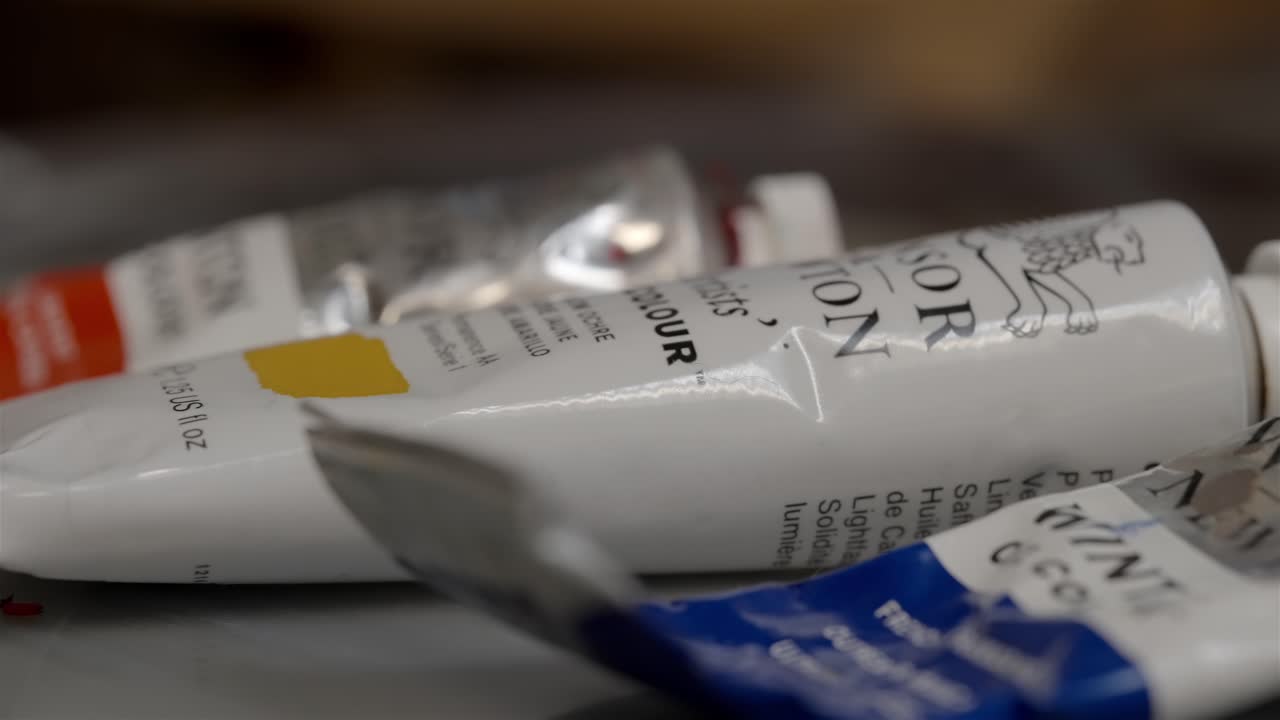 오일 페인트의 튜브와 파란색과  ⁇ 색의 작은  ⁇ 어리들을 가로질러