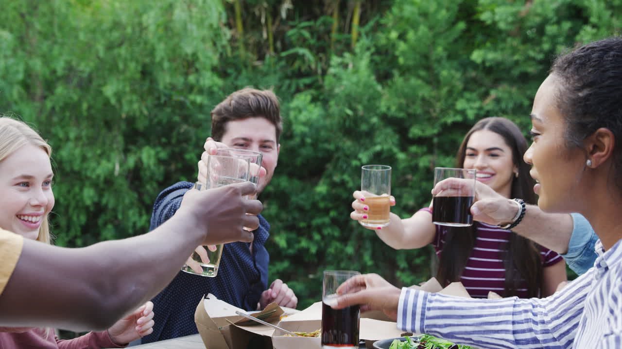 amigos multiculturales haciendo tostadas en el jardín en casa disfrutando de la fiesta de jardín de verano