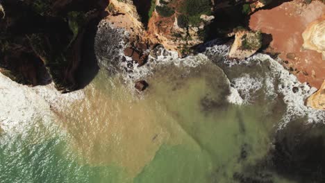 Praia-Dona-Ana-colorful-turquoise-coastline-with-rugged-cliffs-near-Lagos-in-the-Algarve-region-of-Portugal-by-Aerial-4k-drone-top-down-shot