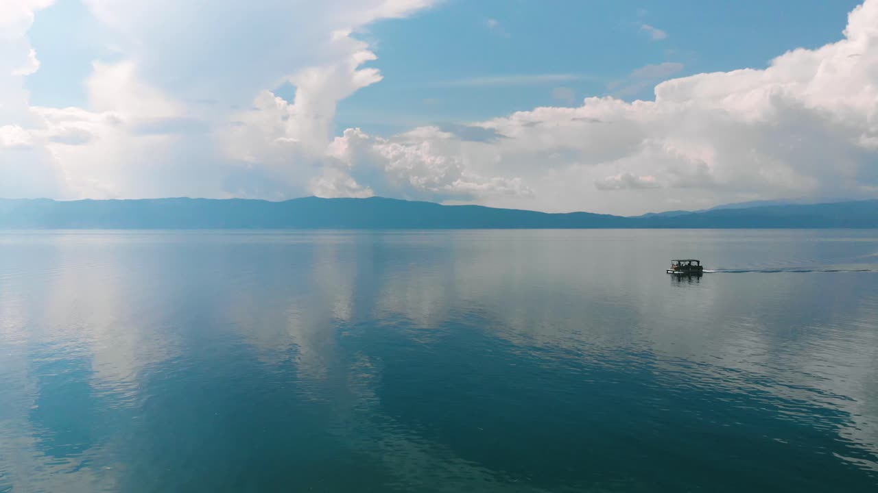 Boat going from right to left on very still blue water.