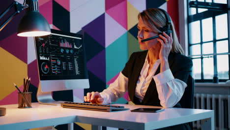 professional woman working on computer with headset analyzing data
