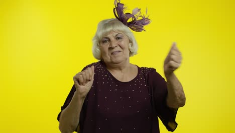 positiva anciana feliz disfrutando de la música de la fiesta, moviéndose en una danza enérgica, celebrando el éxito