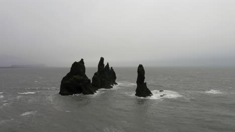 Aerial:-Orbit-shot-of-Reynisdrangar-Rocks-in-a-stormy-sea