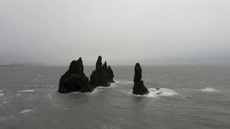 antena: toma en órbita de rocas reynisdrangar en un mar tormentoso
