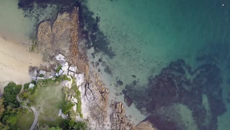 Blick-Nach-Unten-Auf-Eine-Kleine-Sandsteinfelsformation,-Die-Von-Blauem,-Türkisfarbenem-Wasser-Umgeben-Ist