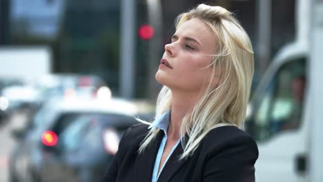 young blond businesswoman is standing on street and looking on side