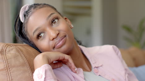 African-American-young-woman-leaning-on-sofa,-looking-relaxed