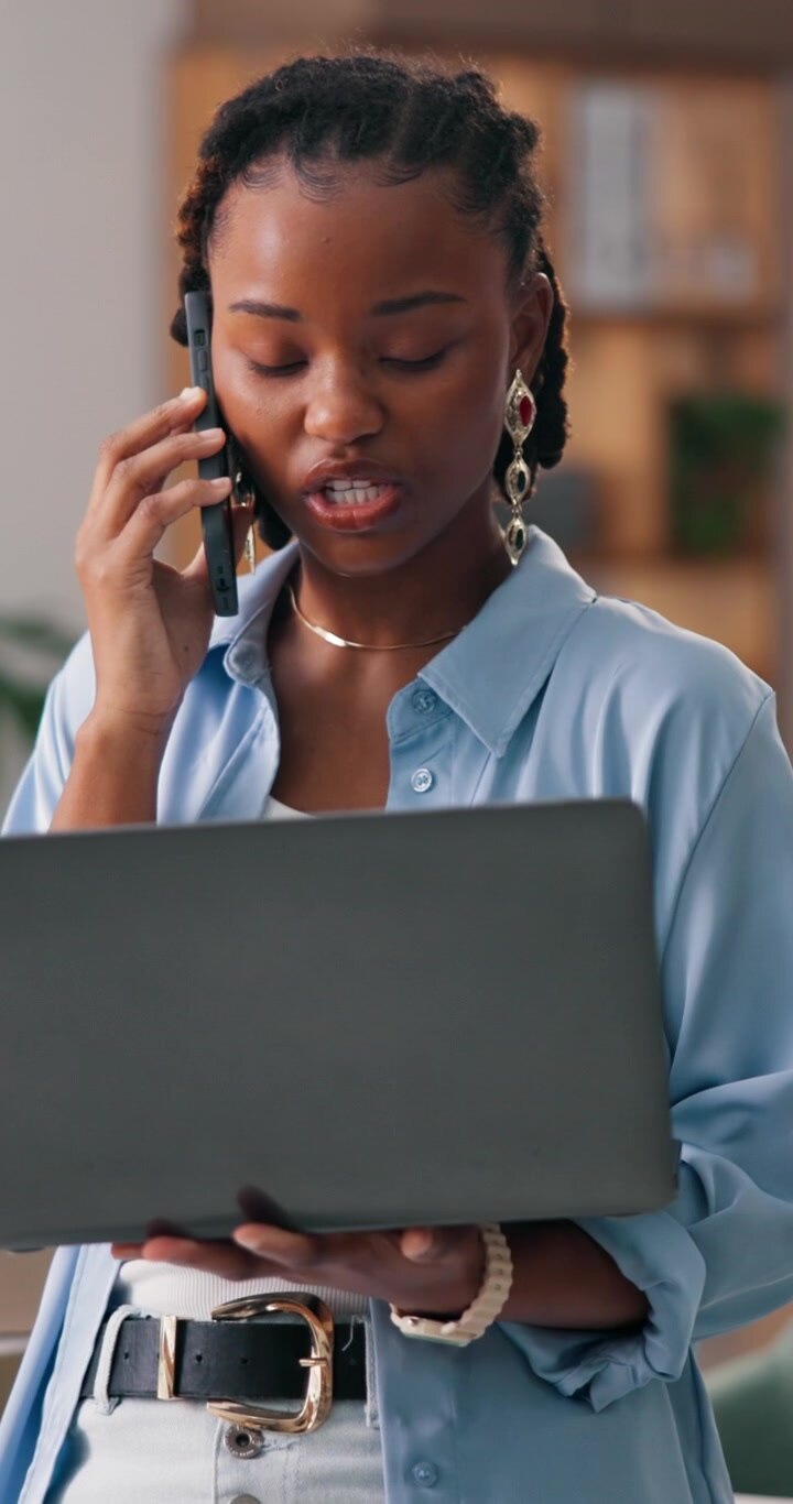 Giovane Donna Professionista al Telefono Mentre Lavora al Computer Portatile