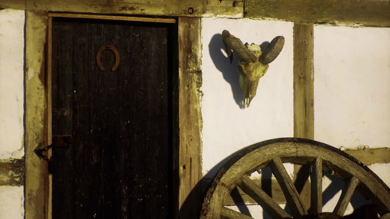 Old wooden wheel and skull decorate rustic building in rural setting